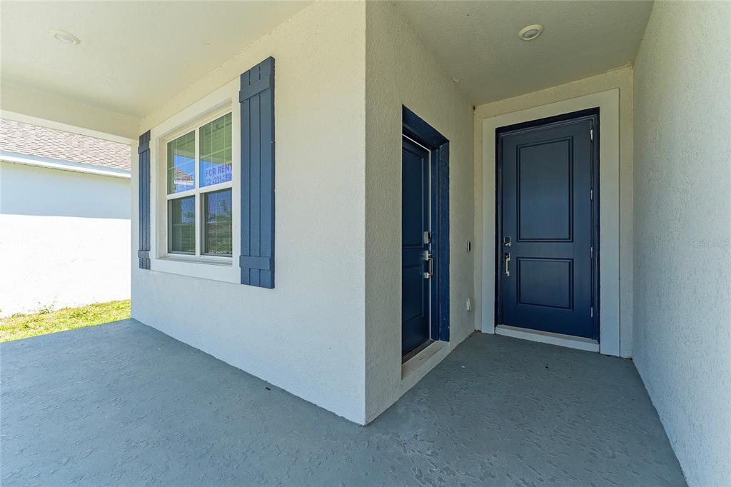 A covered porch features a blue front door, a side door, and a window with shutters — 860 DARING DRIVE, DAVENPORT, FL