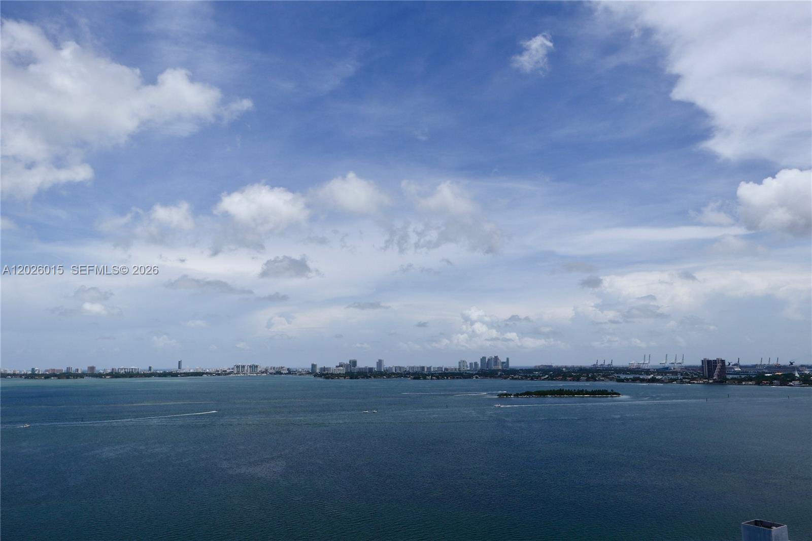 A high-angle view of a bay with a distant city skyline and a small island — 650 NE 32 # 1906, Miami FL 33137, MIAMI, FL