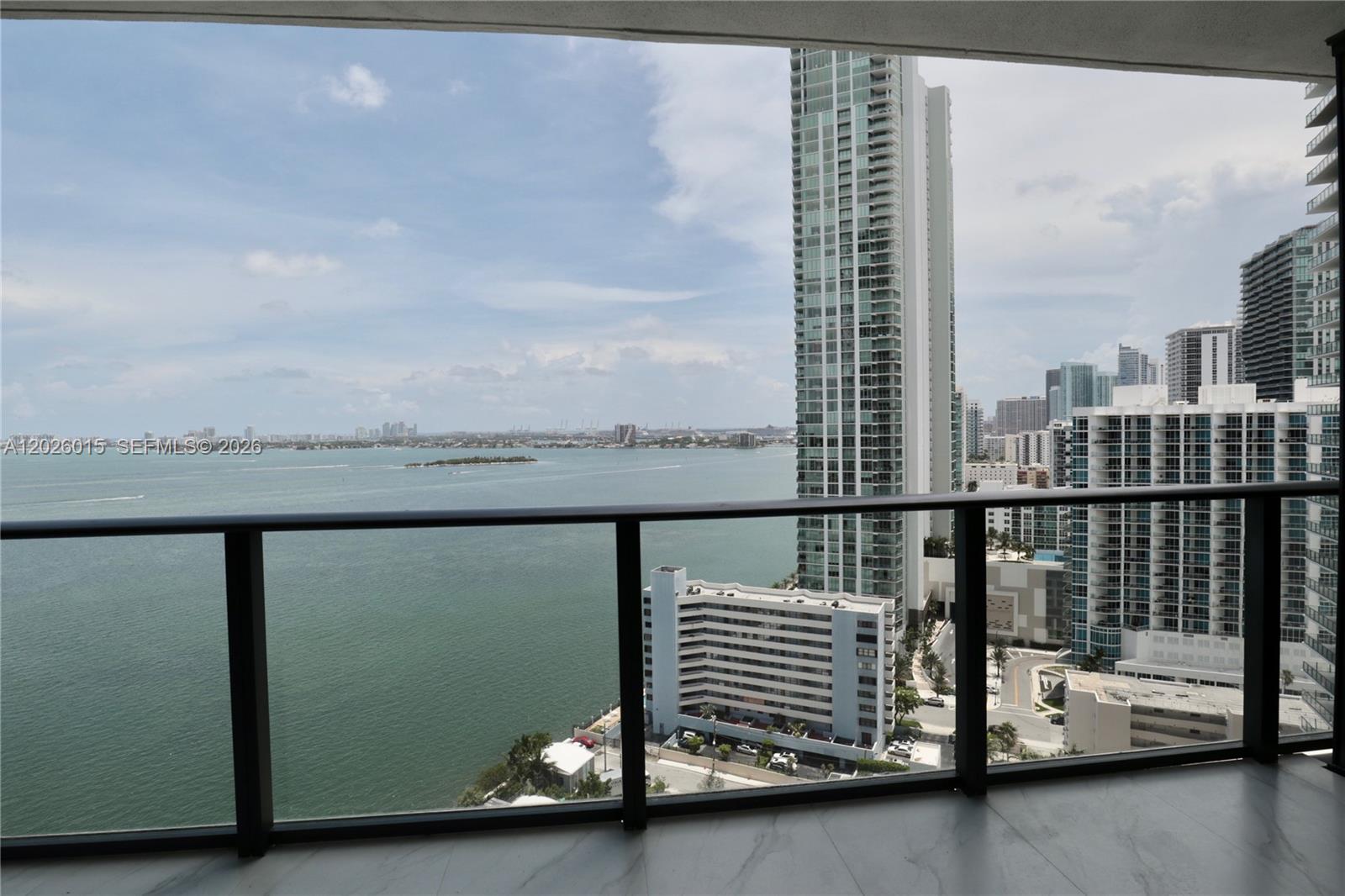 A balcony with a glass railing overlooks a bay and surrounding high-rise buildings — 650 NE 32 # 1906, Miami FL 33137, MIAMI, FL
