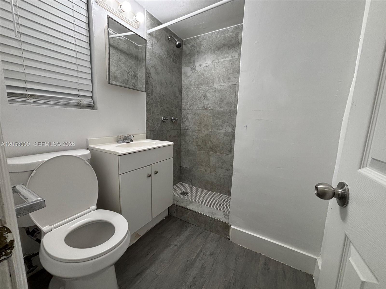 A bathroom features a white vanity, a toilet, and a tiled walk-in shower — 1843 Dewey St # 121, Hollywood FL 33020, HOLLYWOOD, FL