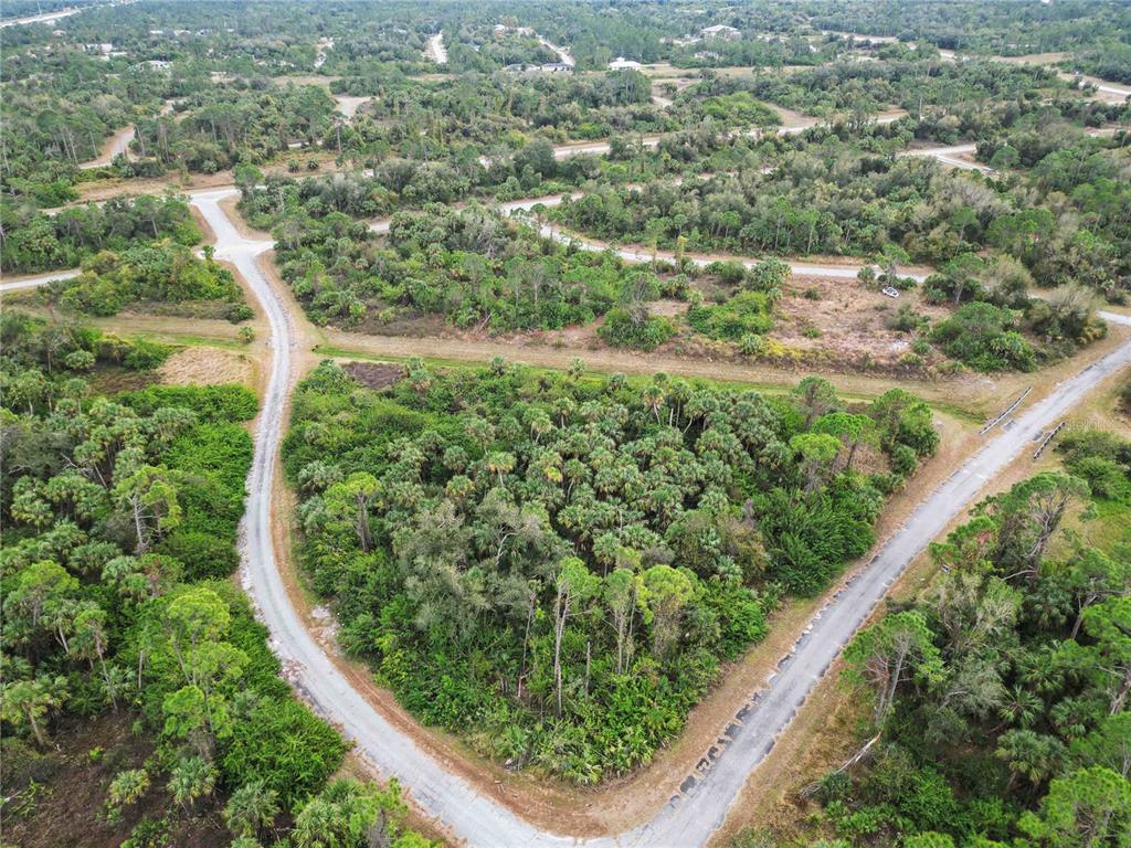 An aerial view of a triangular, wooded vacant lot bordered by paved roads — CANYON TERRACE, NORTH PORT, FL