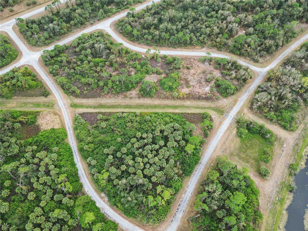 An aerial view shows undeveloped residential lots with dirt roads and dense vegetation — CANYON TERRACE, NORTH PORT, FL