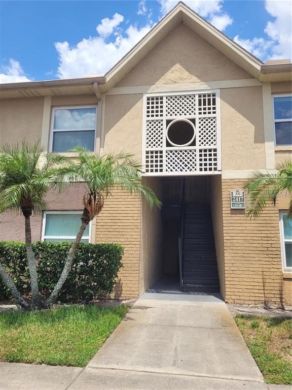 A two-story tan building features a central staircase, decorative lattice paneling, and palm trees — 2417 BARLEY CLUB COURT UNIT 6, ORLANDO, FL