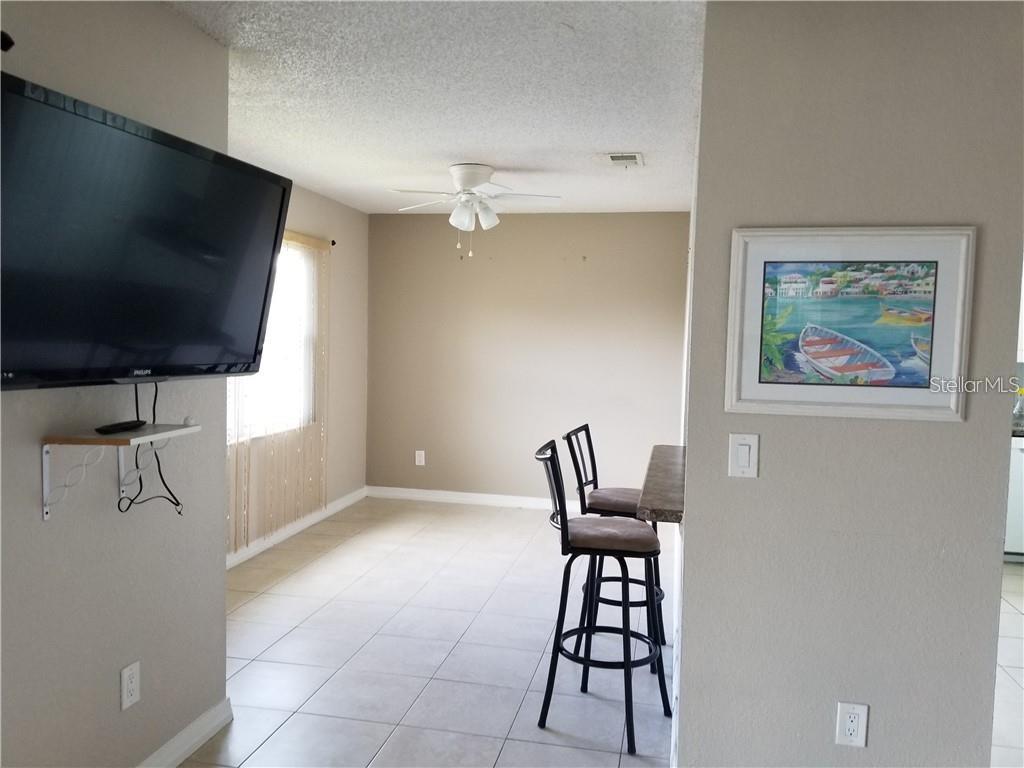 A living area features tile flooring, a ceiling fan, and a breakfast bar with stools — 2417 BARLEY CLUB COURT UNIT 6, ORLANDO, FL