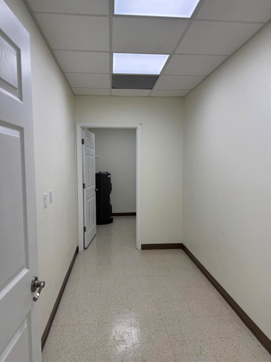 A narrow hallway with white walls, a drop ceiling, and a doorway leading to a utility room — 3205 Medical Way, Sebring FL 33870, SEBRING, FL