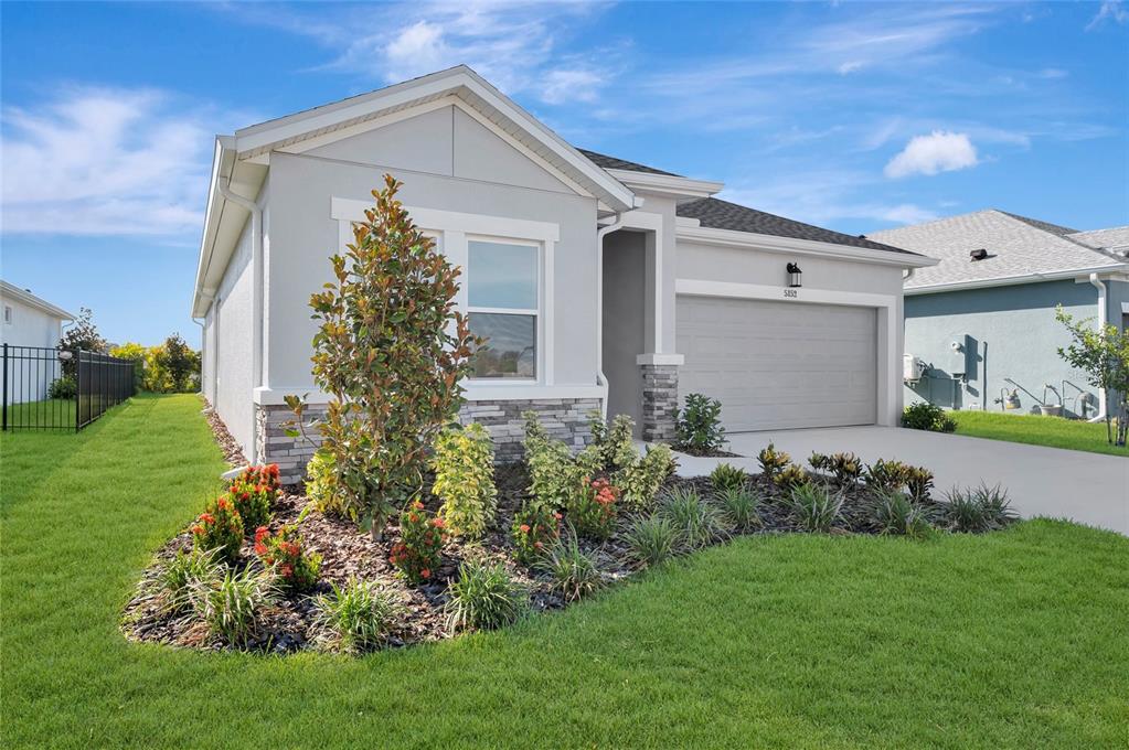 A single-story house with a gray exterior, stone accents, a two-car garage, and landscaping — 5152 CREEK SAND DRIVE, APOLLO BEACH, FL