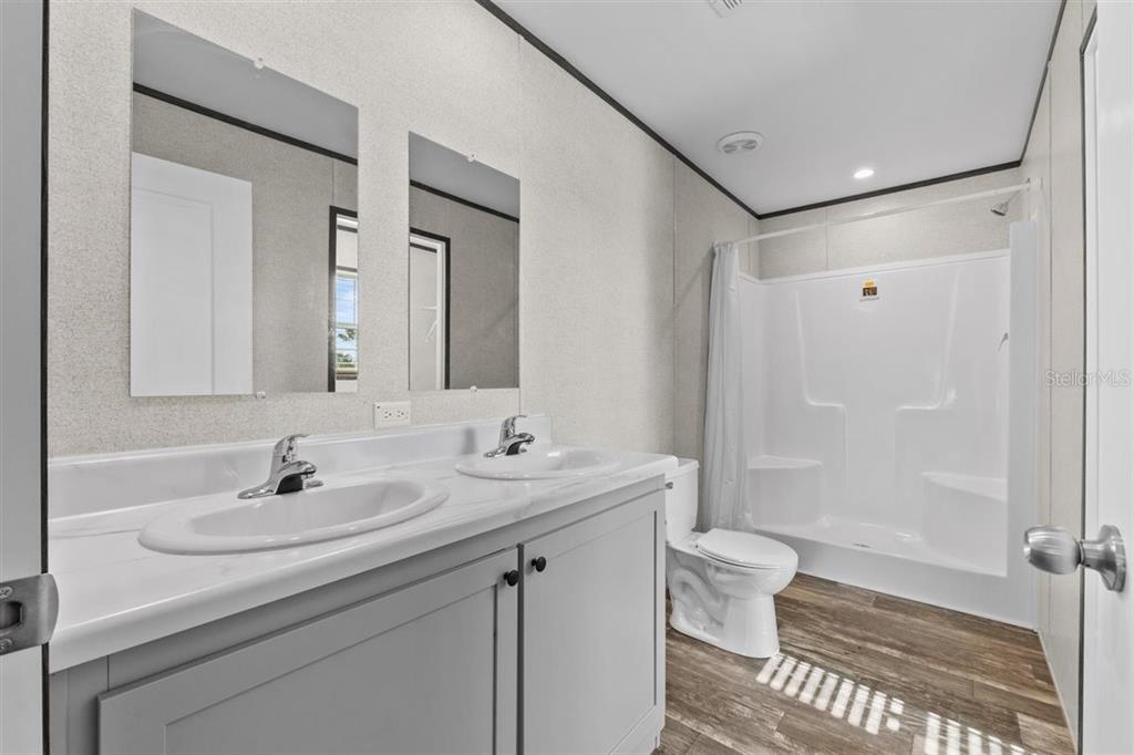 A bathroom features a double vanity with gray cabinets, a toilet, and a shower stall — 8457 N CAROUSEL TERRACE, CRYSTAL RIVER, FL