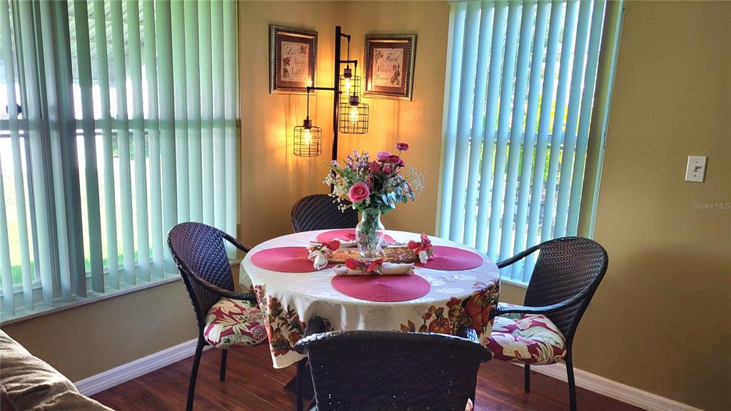 A dining area features a round table with four wicker chairs and vertical window blinds — 9660 44TH STREET N, PINELLAS PARK, FL