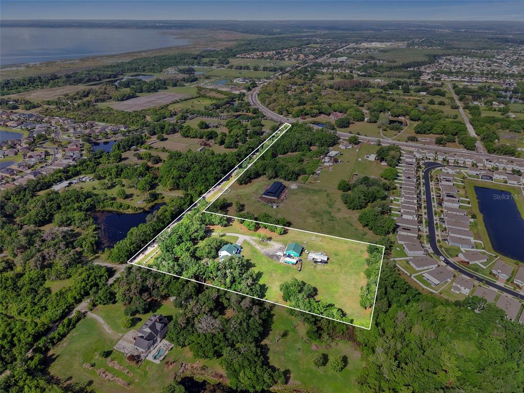 An aerial view shows a rural property with two houses and outbuildings outlined in white — 4385 SEMORAN FARMS ROAD, KISSIMMEE, FL