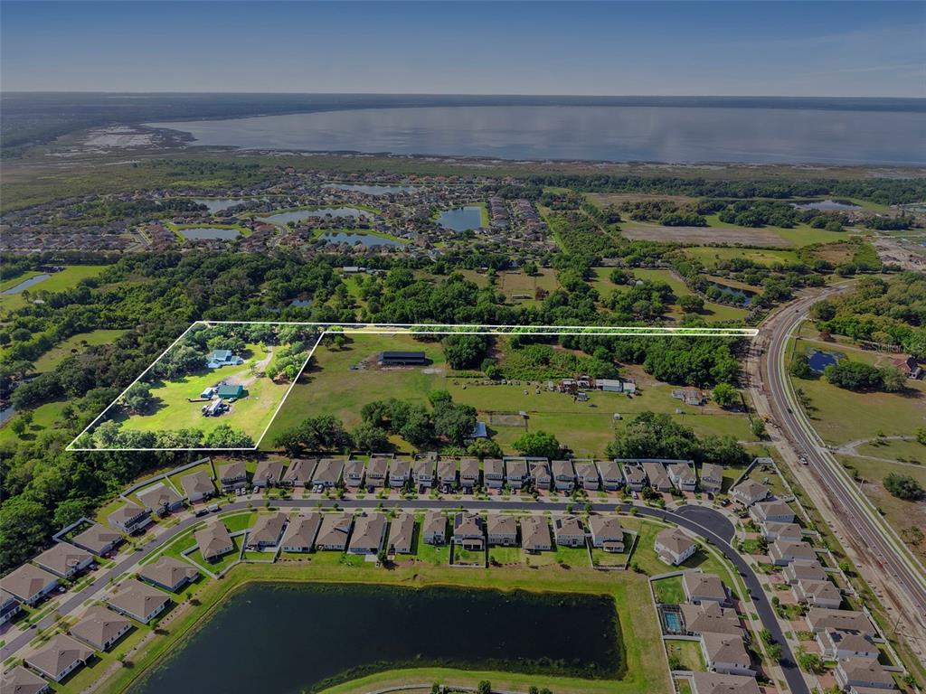 An aerial view shows a large, partially wooded property outlined in white near a residential development — 4385 SEMORAN FARMS ROAD, KISSIMMEE, FL