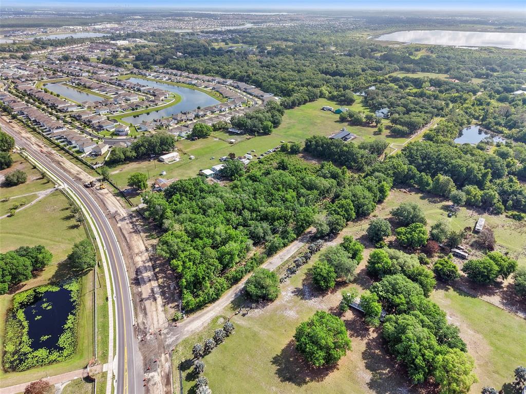 An aerial view shows a road bordering a large wooded lot near a residential neighborhood — 4385 SEMORAN FARMS ROAD, KISSIMMEE, FL