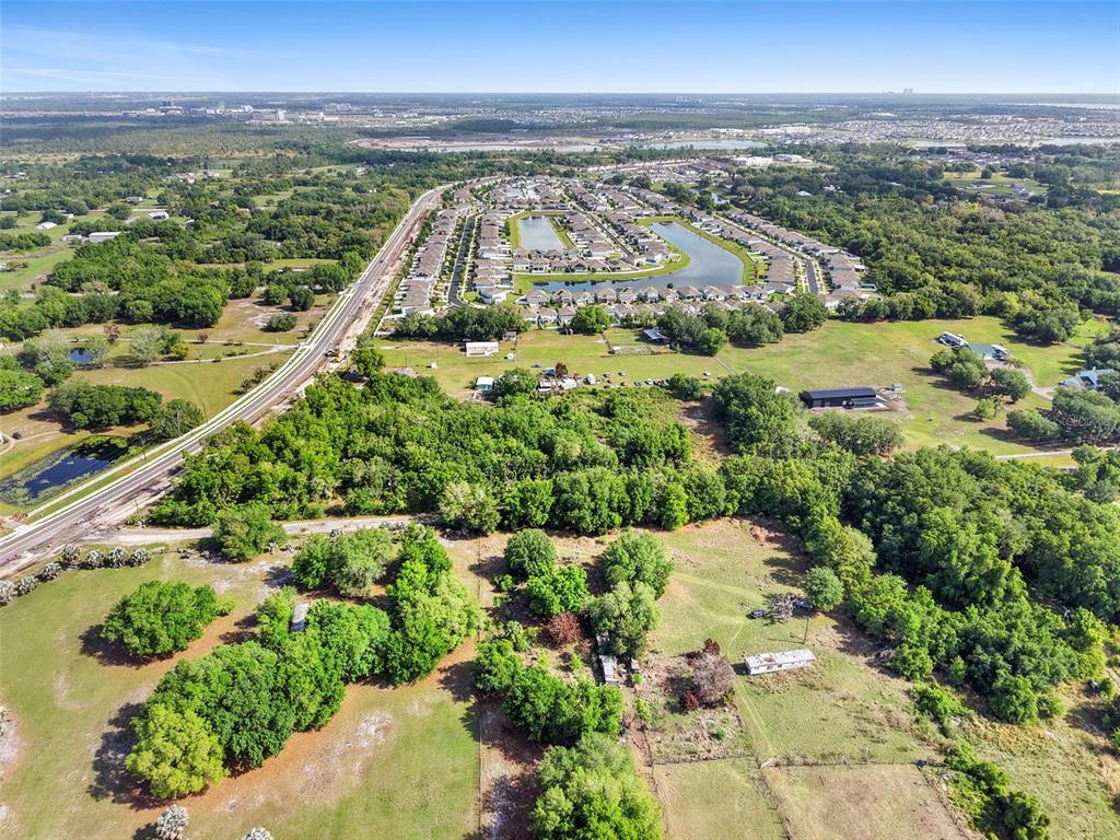 An aerial view shows a residential neighborhood, a road, and surrounding wooded land — 4385 SEMORAN FARMS ROAD, KISSIMMEE, FL