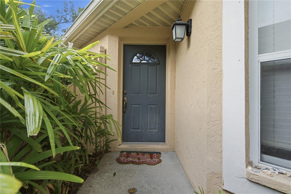 A gray front door with a small arched window sits under a tan overhang — 3225 GULF WATCH COURT, SARASOTA, FL