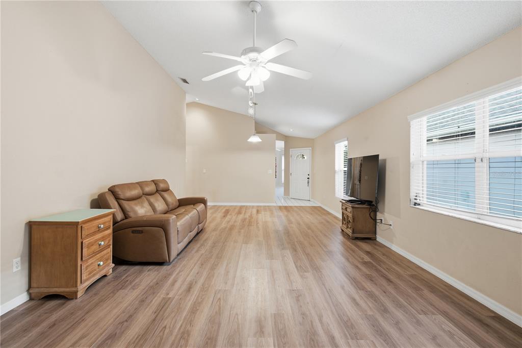A living room features light wood-look flooring, a brown leather sofa, and a ceiling fan — 3225 GULF WATCH COURT, SARASOTA, FL
