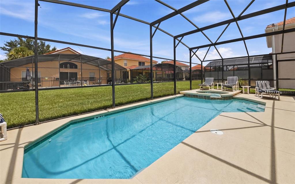 A screened-in swimming pool and spa with lounge chairs on a concrete patio — 216 SEVILLA AVENUE, DAVENPORT, FL