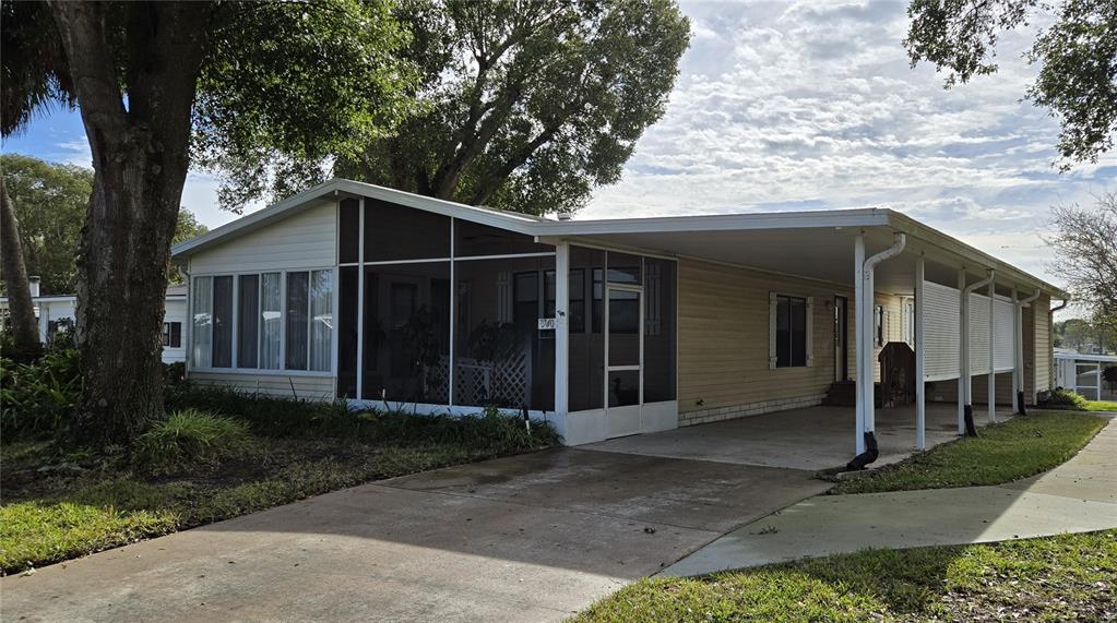 A single-story manufactured home features a screened-in porch, a carport, and light-colored siding — 3740 N CITRUS CIRCLE UNIT 709, ZELLWOOD, FL