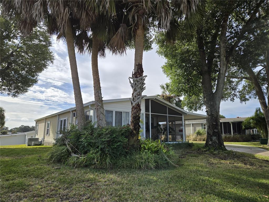 A light-colored mobile home features a screened-in porch and tall palm trees in front — 3740 N CITRUS CIRCLE UNIT 709, ZELLWOOD, FL