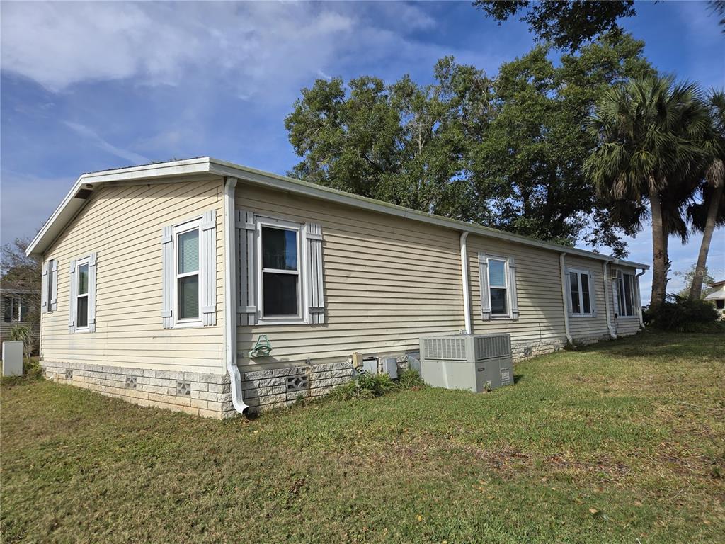 A side view of a beige manufactured home with light-colored brick skirting and vinyl siding — 3740 N CITRUS CIRCLE UNIT 709, ZELLWOOD, FL