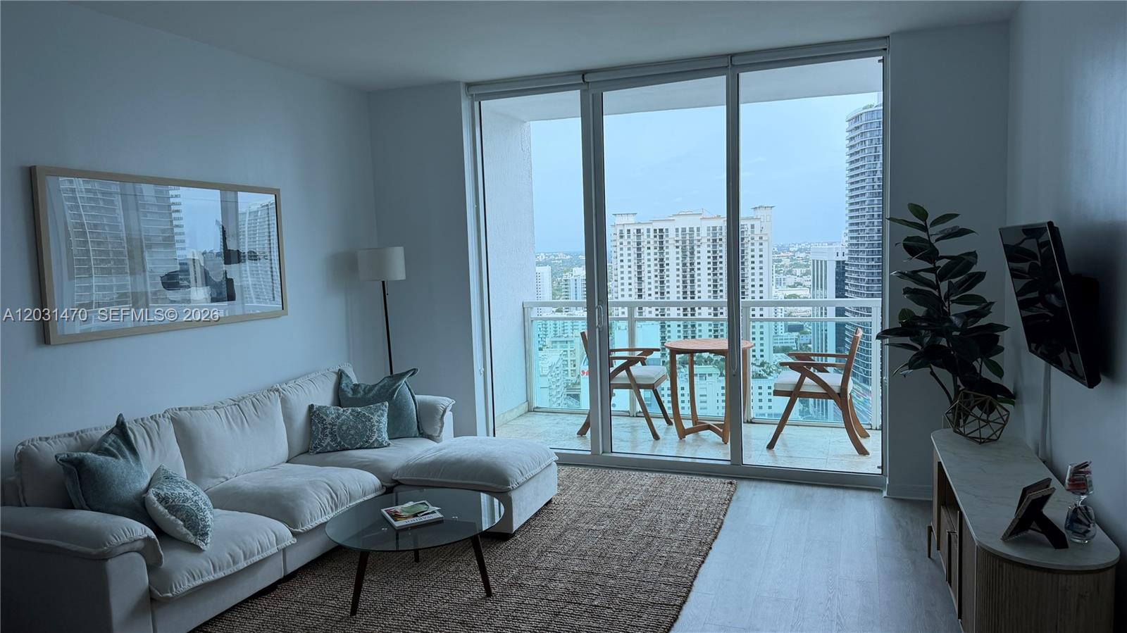 A living room features a white sectional sofa, glass coffee table, and balcony with city views — MIAMI, FL