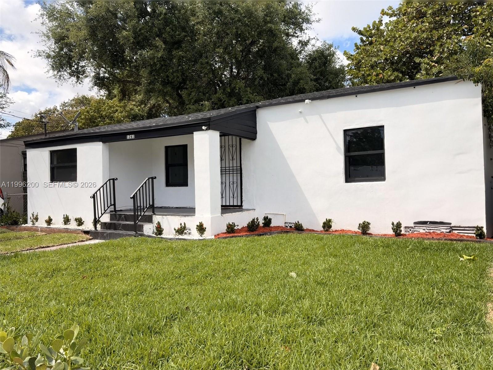 A white single-story house features a black roof, black window frames, and a front porch — 1261 NW 45th St, Miami FL 33142, MIAMI, FL