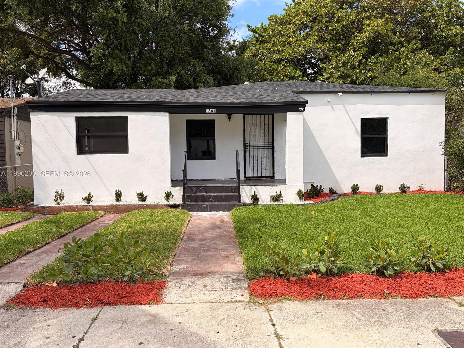 A single-story white house with a black roof, dark trim, and a small front porch — 1261 NW 45th St, Miami FL 33142, MIAMI, FL