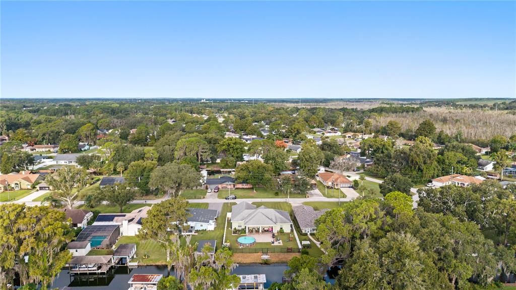 An aerial view shows a residential neighborhood with houses, trees, and a canal — 35638 CALLA COURT, LEESBURG, FL