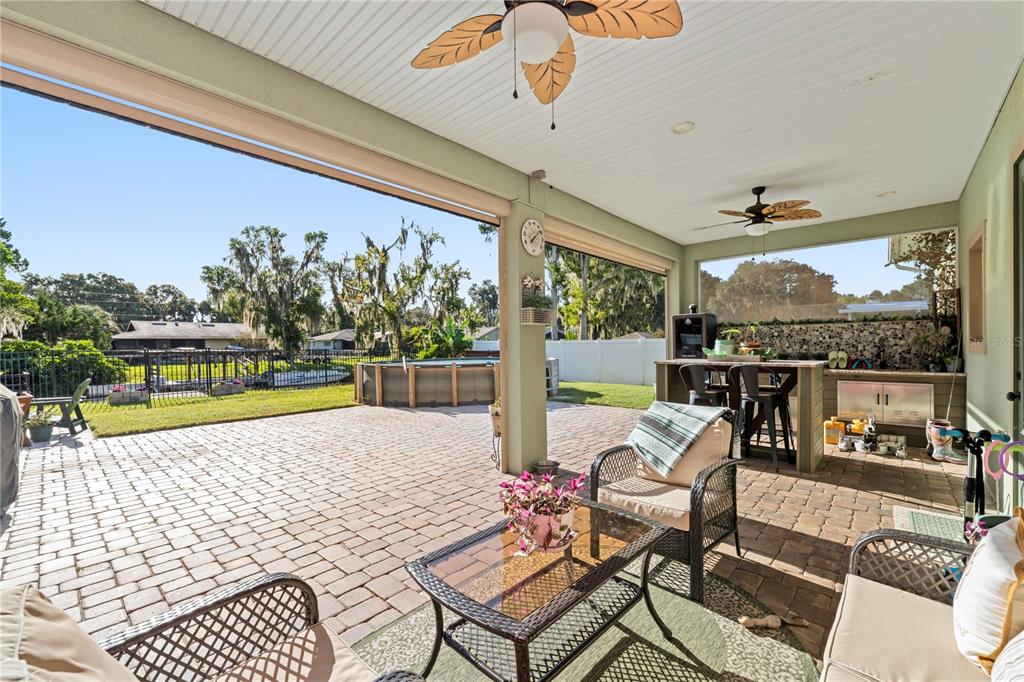 A covered patio features a brick paver floor, outdoor kitchen, and views of a backyard pool — 35638 CALLA COURT, LEESBURG, FL