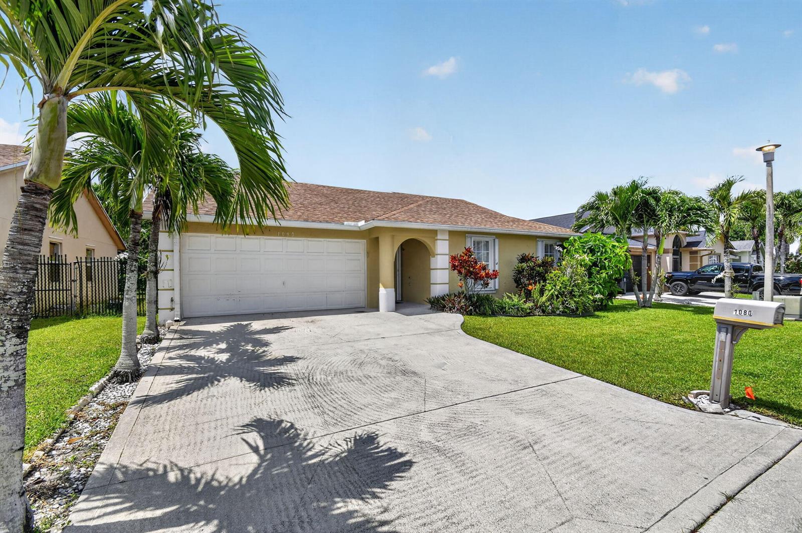 A single-story house with a tan exterior, a two-car garage, and a concrete driveway — 1080 Salmon Isle, FL 33413, FL