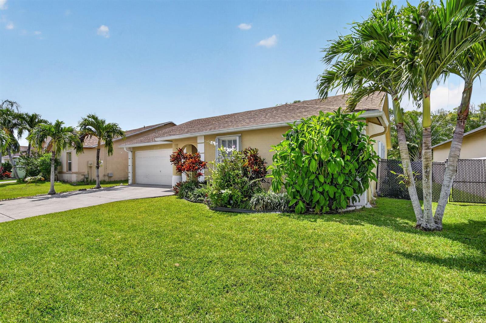 A single-story house with a beige exterior, a concrete driveway, and palm trees in front — 1080 Salmon Isle, FL 33413, FL