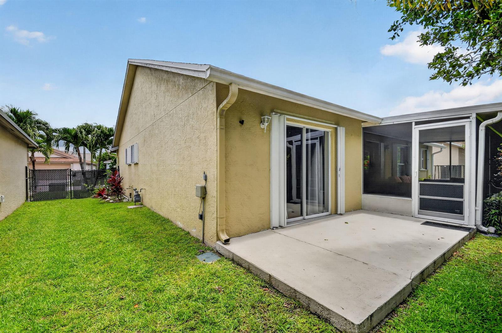 A beige house exterior features a concrete patio, sliding glass doors, and a screened-in porch — 1080 Salmon Isle, FL 33413, FL