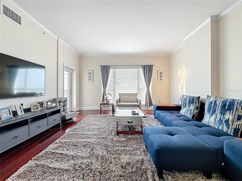 A living room features a blue sectional sofa, a large area rug, and a television — 2305 EDGEWATER DRIVE UNIT 1404, ORLANDO, FL