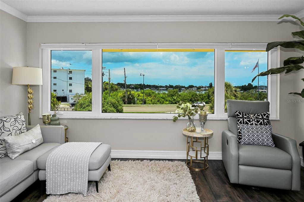 A living room features light gray sofas, a white shag rug, and large windows with views — 100 BLUFF VIEW DRIVE UNIT 211C, BELLEAIR BLUFFS, FL