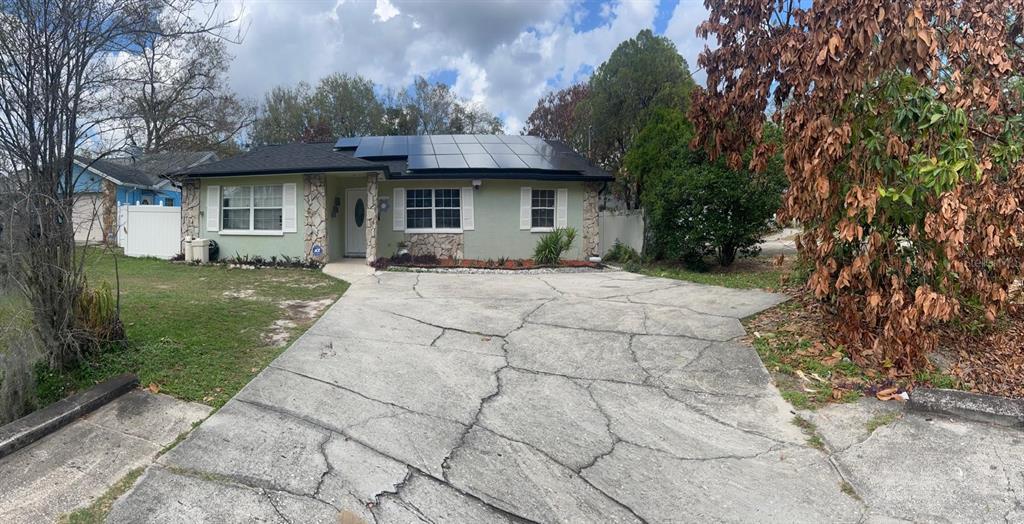 A single-story house with a cracked concrete driveway and solar panels on the roof — 4912 E SERENA DRIVE, TAMPA, FL