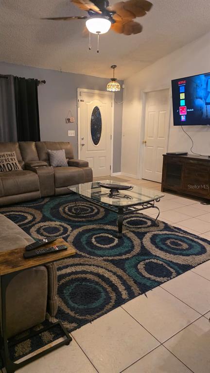 A living room features a brown sectional sofa, a glass coffee table, and a patterned rug — 4912 E SERENA DRIVE, TAMPA, FL
