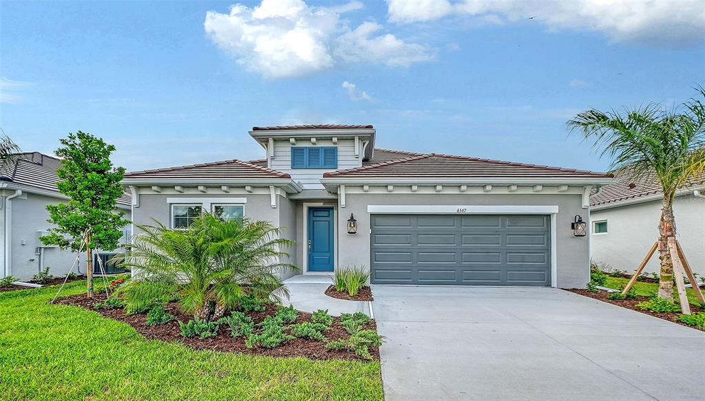 A single-story house with a gray exterior, a blue front door, and a two-car garage — 6547 BIG BAYOU DRIVE, SARASOTA, FL