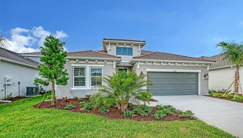 A single-story house with a gray garage, a palm tree, and a small front yard — 6547 BIG BAYOU DRIVE, SARASOTA, FL