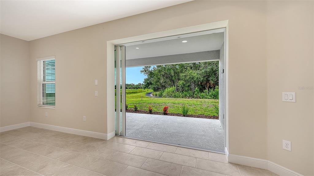An interior room with tile flooring features a large sliding glass door opening to a patio — 6547 BIG BAYOU DRIVE, SARASOTA, FL