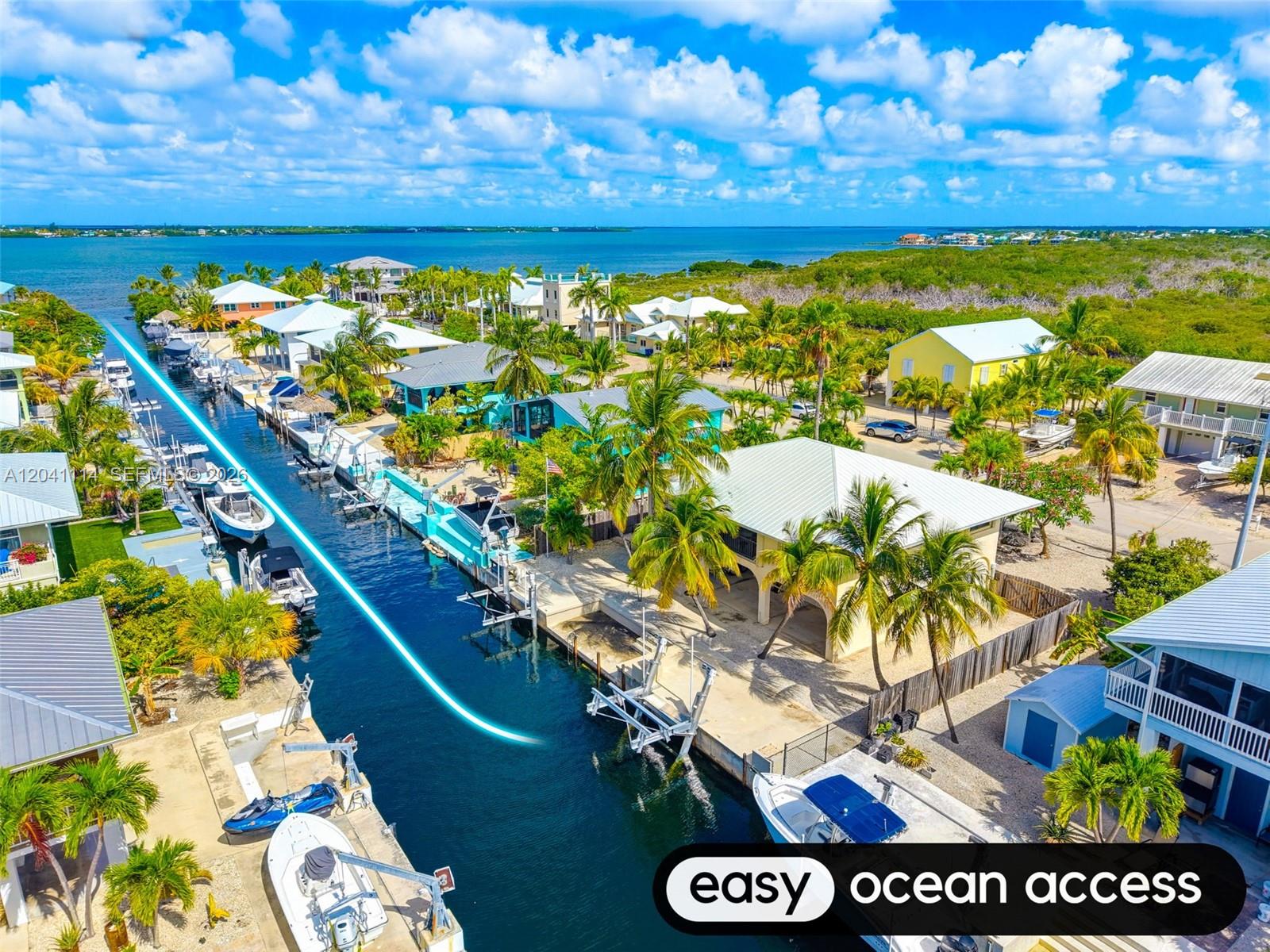An aerial view shows a canal-front property with a boat dock and tropical landscaping — BIG PINE, FL