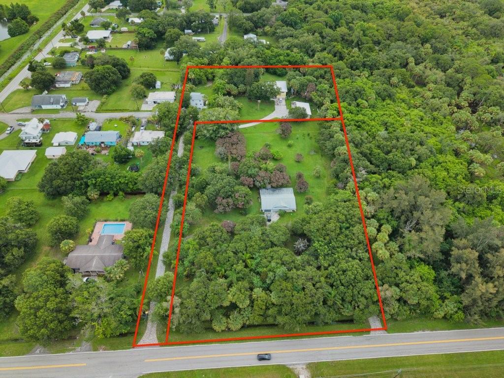 An aerial view shows a large, tree-filled residential lot outlined in red along a road — 711 S 21ST STREET, FORT PIERCE, FL