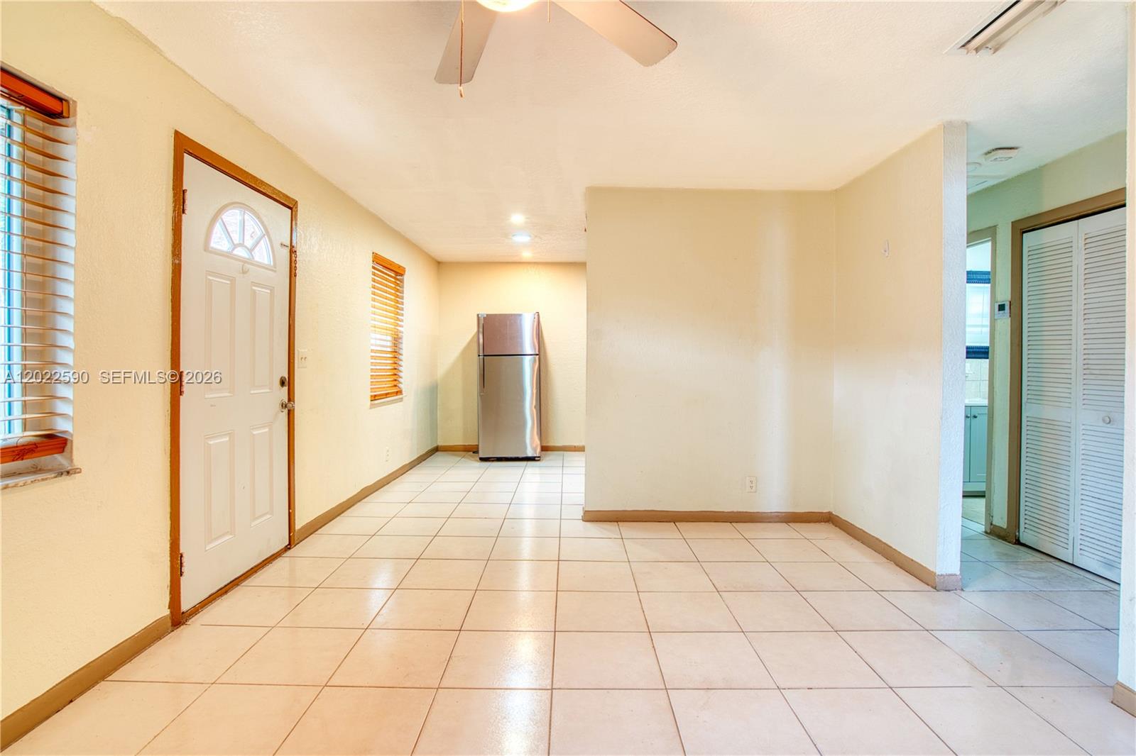 A room with light-colored tile flooring, a stainless steel refrigerator, and a white entry door — 129 SE 4th Ave # 1, Hallandale Beach FL 33009, HALLANDALE BEACH, FL