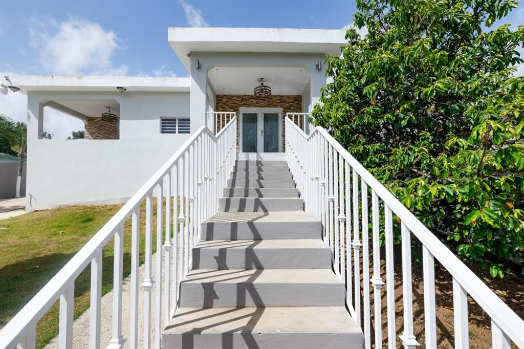 A set of concrete stairs with white railings leads to the front entrance of a house — 843 SECT LOS RAMOS, TRUJILLO ALTO, PR
