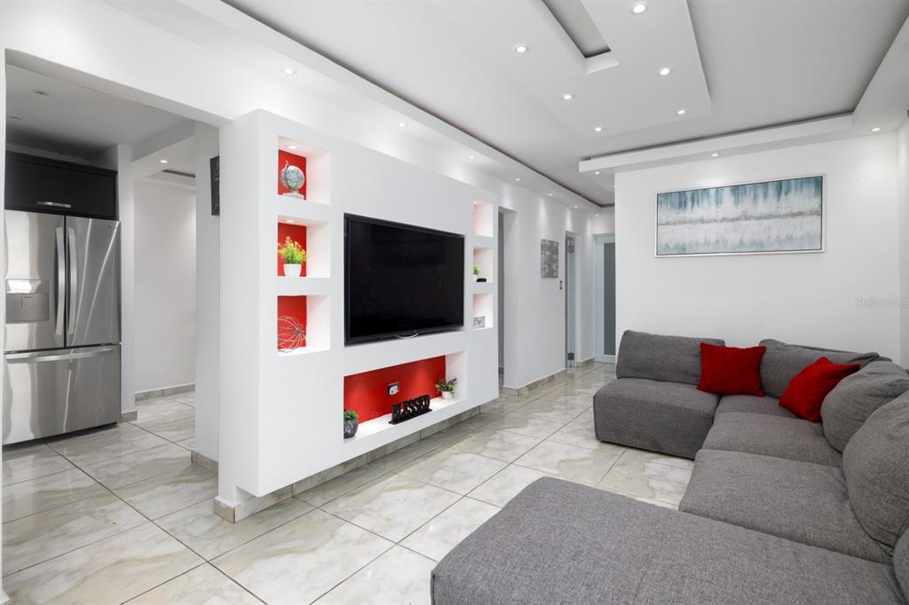 A living room features a large grey sectional, white tile floors, and a built-in media wall — 843 SECT LOS RAMOS, TRUJILLO ALTO, PR