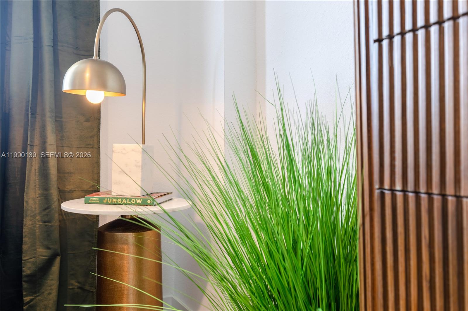 A side table with a lamp and book sits next to a tall green plant — 1005 Spring Garden Rd # 530, Miami FL 33136, MIAMI, FL