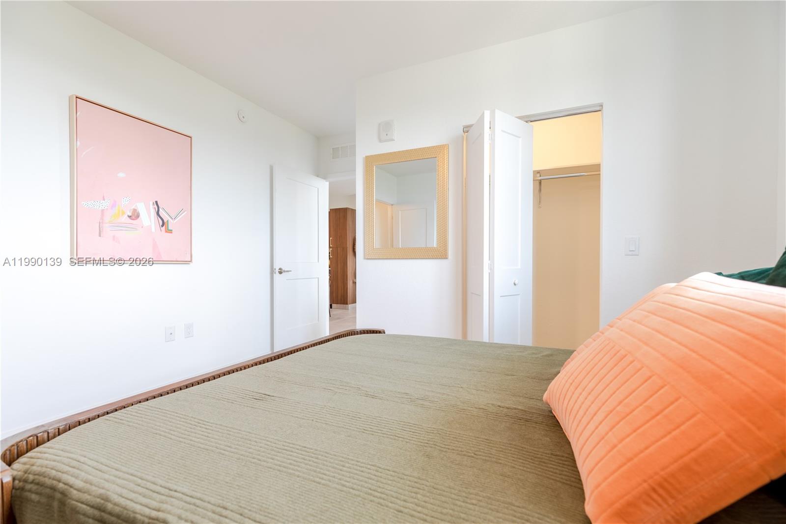 A bedroom features a bed with green bedding, a pink wall art piece, and a closet — 1005 Spring Garden Rd # 530, Miami FL 33136, MIAMI, FL