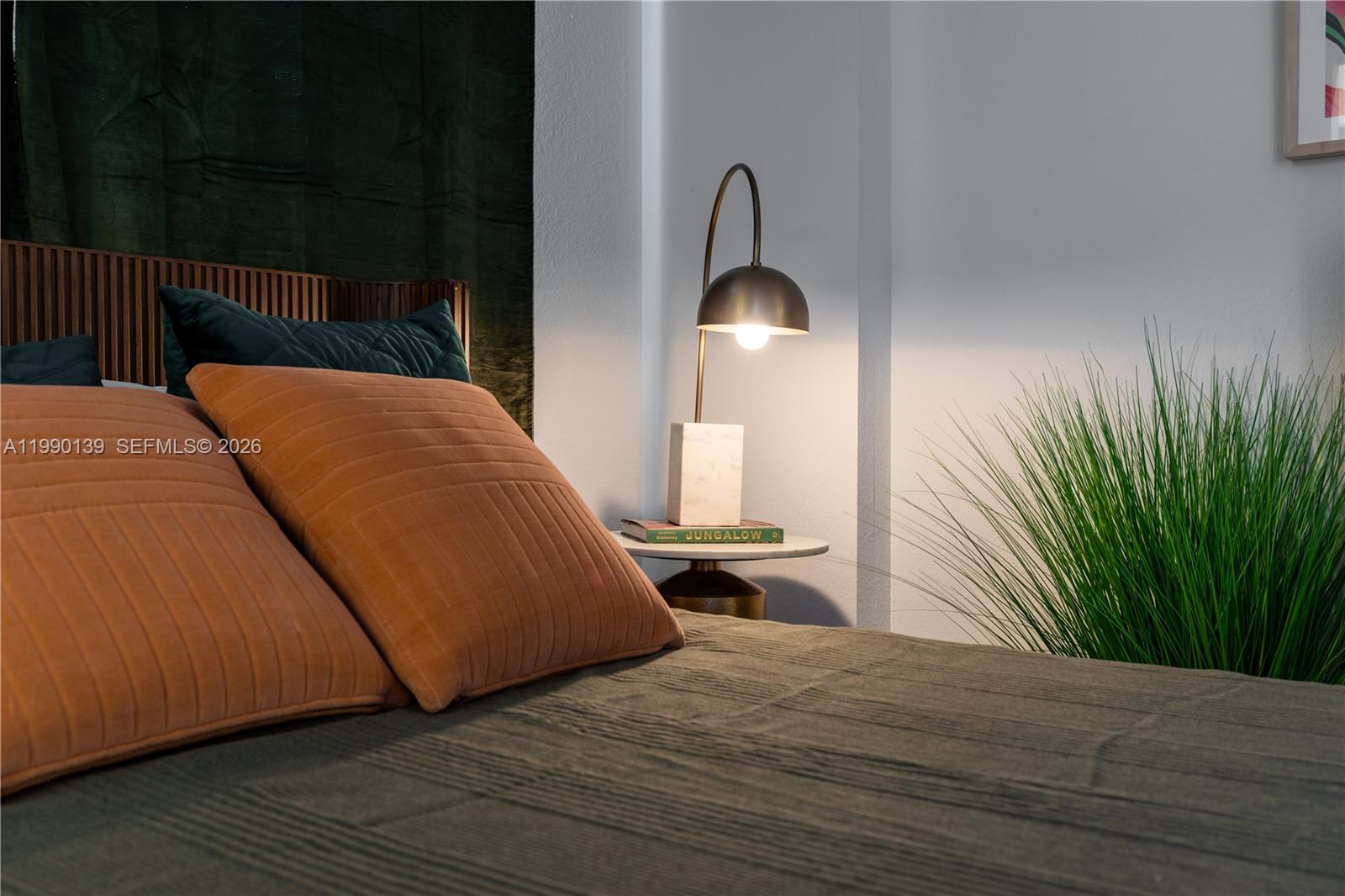 A bedroom features a bed with orange pillows, a small side table, and a lamp — 1005 Spring Garden Rd # 530, Miami FL 33136, MIAMI, FL