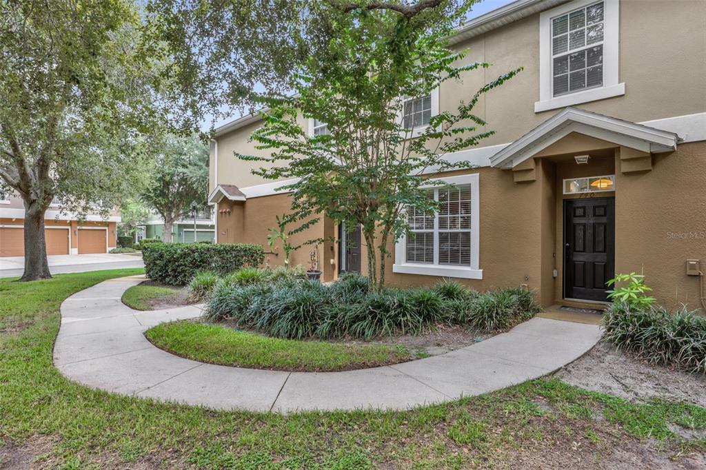 A tan two-story townhouse exterior features a black front door and a curved concrete walkway — 740 ASHWORTH OVERLOOK DRIVE UNIT B, APOPKA, FL