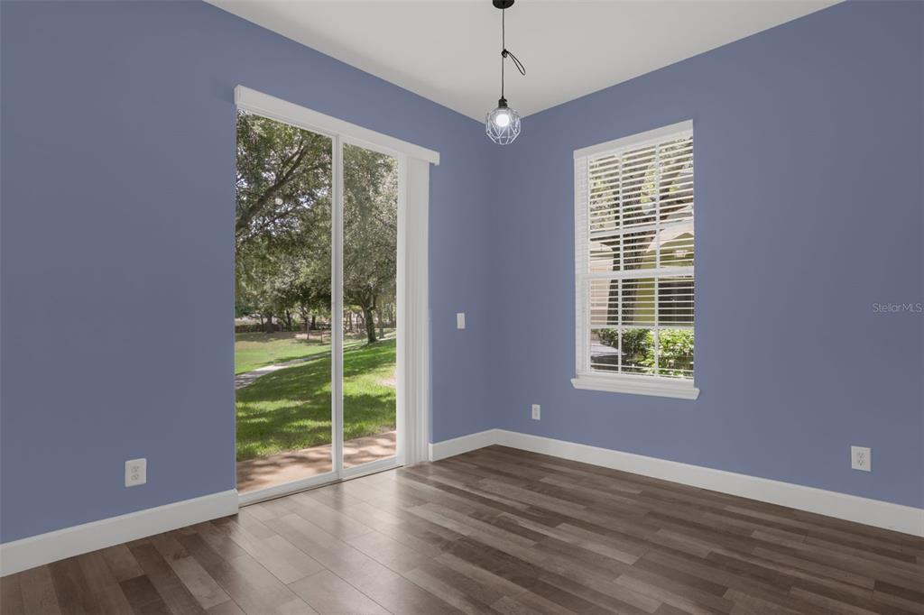 An empty room with blue walls, wood-look flooring, a sliding glass door, and a window — 740 ASHWORTH OVERLOOK DRIVE UNIT B, APOPKA, FL