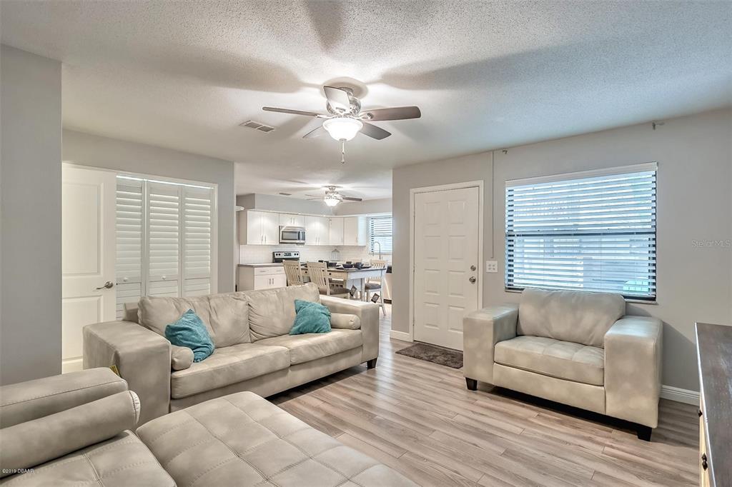 A living room with light-colored furniture, wood-look flooring, and an open view to the kitchen — 3656 JACKSON STREET UNIT 10, PORT ORANGE, FL