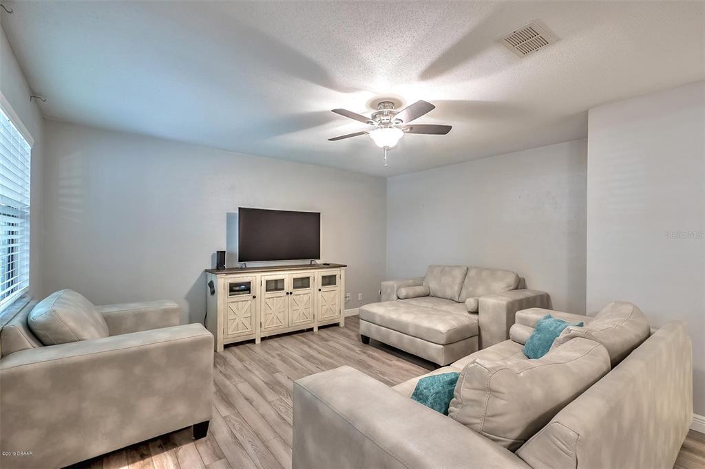 A living room features light gray walls, wood-look flooring, a ceiling fan, and matching furniture — 3656 JACKSON STREET UNIT 10, PORT ORANGE, FL