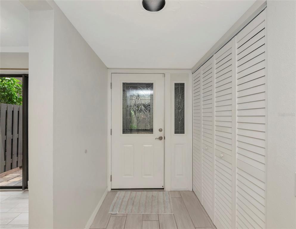 An entryway features a white front door with a glass insert, tile flooring, and louvered closets — 108 WOODLAND PLACE UNIT 108, OSPREY, FL